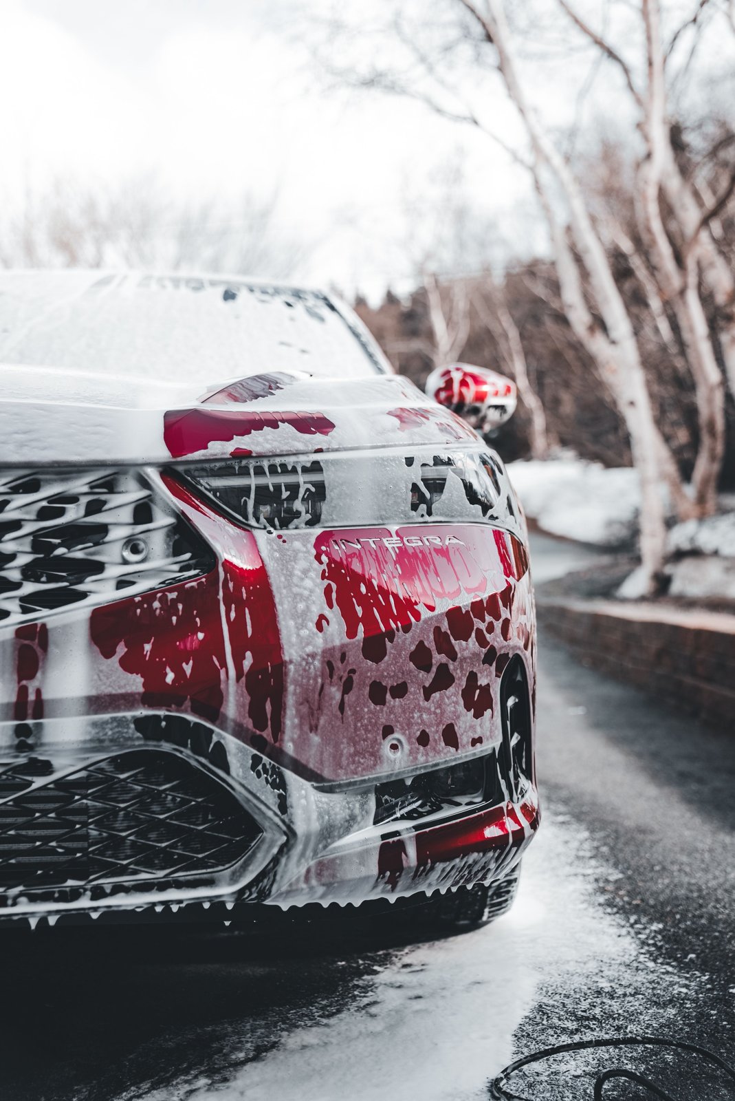 Red Acura Integra covered in foam during a hand wash